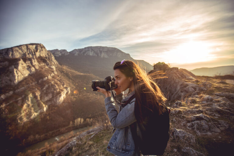 Young woman hiker taking photo at mountain peak